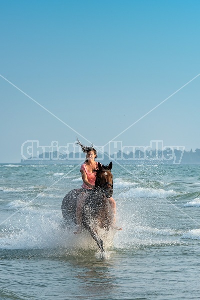 Young woman horseback riding in the surf of Lake Ontario. 