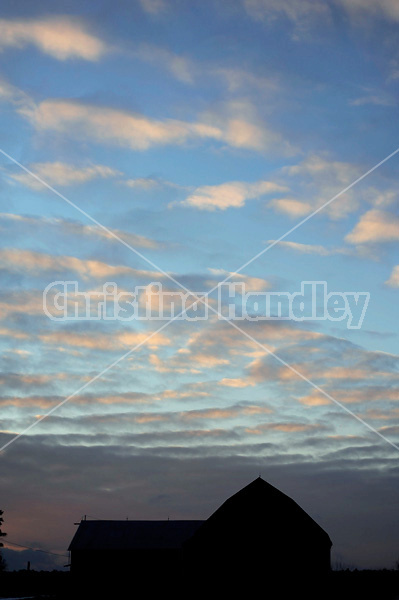 Silhouette photo of barn against colorful sky