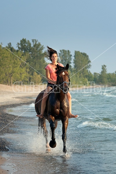 Young woman horseback riding in the surf of Lake Ontario. 