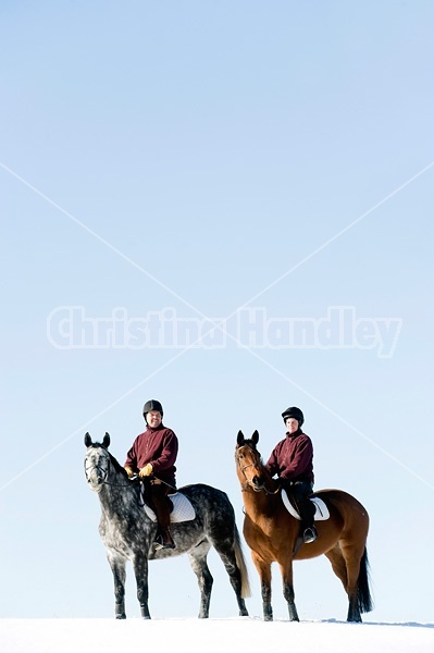 Husband and wife horseback riding through the deep snow