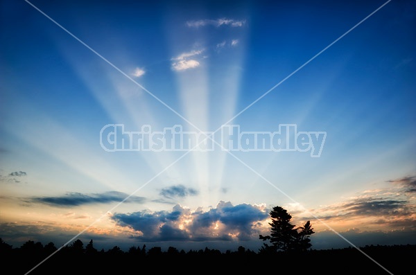 Rays of sunshine streaming out from behind clouds during sunrise