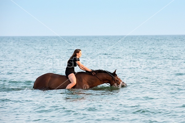 Young woman horseback riding in Lake Ontario