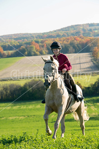 Young woman riding palomino horse