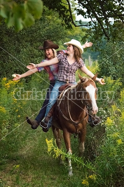 Two young women riding double in a western saddle