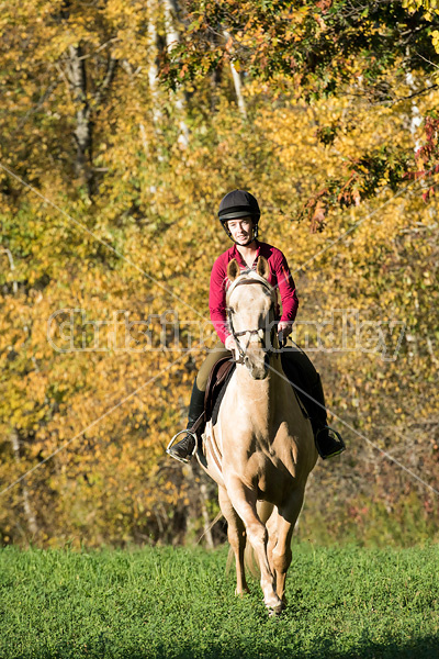 Young woman riding palomino horse