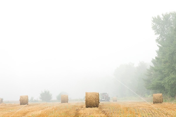 Farmer baling round bales of straw